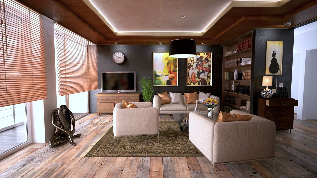 The interior of a bright, modern living room with minimalist furniture and large glass doors opening to a beach and ocean view.