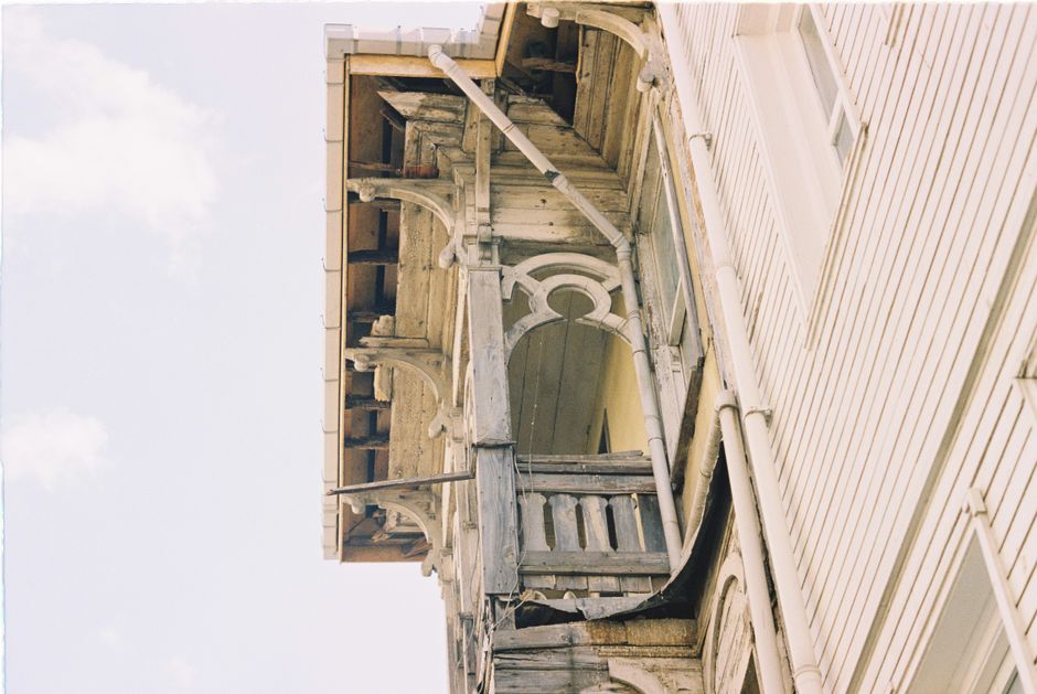 A close-up of a historic New Orleans home, focusing on the intricate ironwork of a balcony and classic shutters, representing the beauty and complexity of older properties.